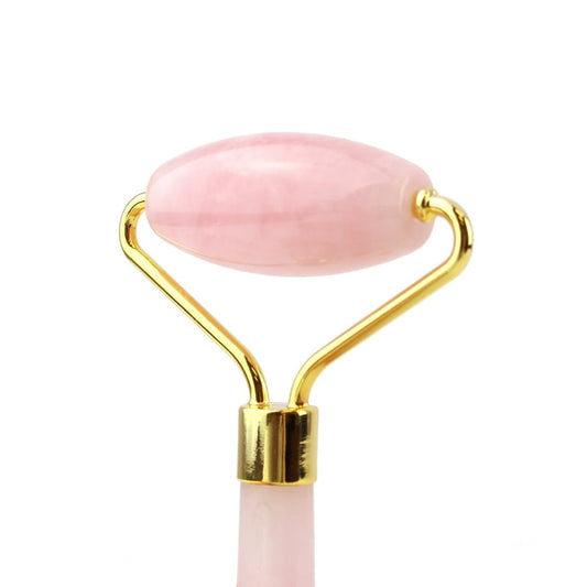 Pink facial roller with gold accents on a white background